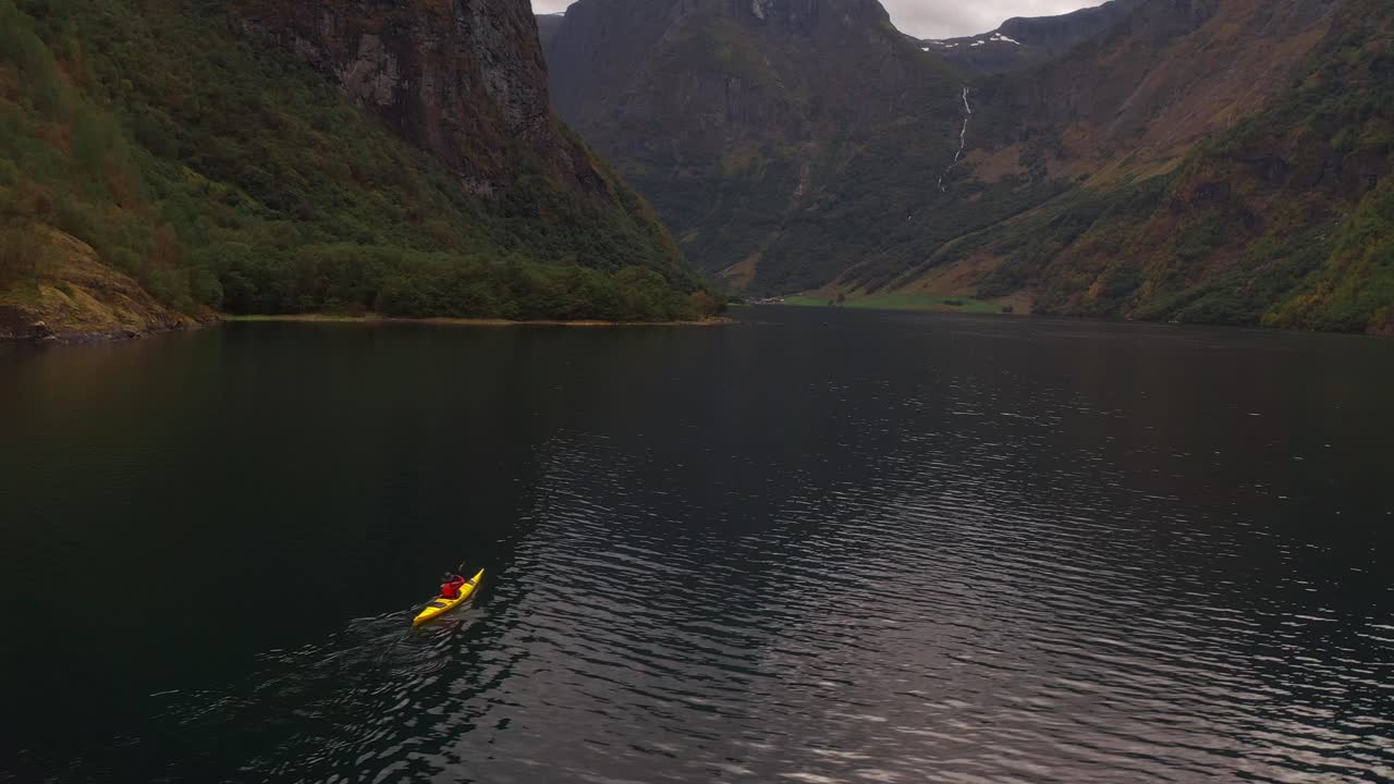 Kajakpaddlare paddlar genom en lugn norsk fjord omgiven av branta berg.