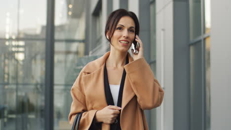 vista frontal de la mujer de negocios hablando por teléfono mientras camina por la calle