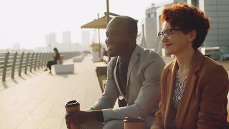 Diverse-Colleagues-Talking-over-Coffee-on-Urban-Embankment