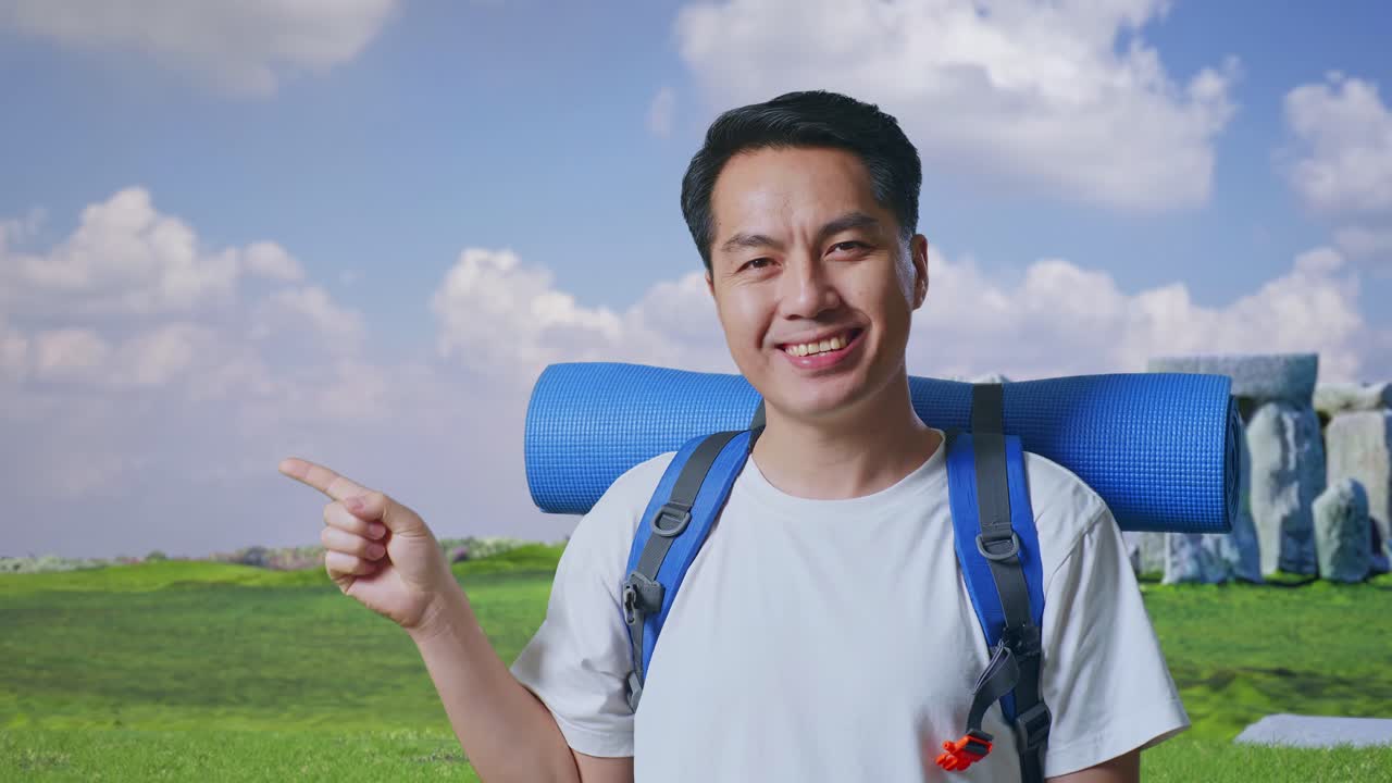Close Up Of Asian Male Hiker With Mountaineering Backpack Smiling And Pointing To Side While Traveling In Stonehenge