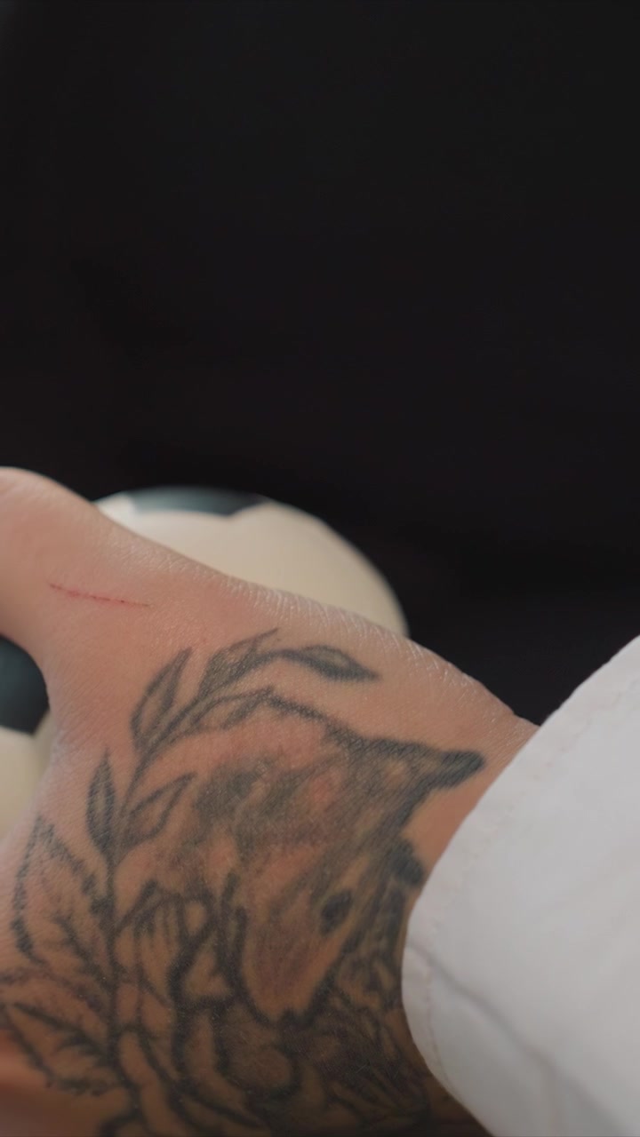 Primer plano de la mano de una persona con tatuajes detallados. El enfoque se mantiene constante, resaltando los intrincados diseños de los tatuajes. Un pequeño rasguño rojo es visible cerca de un dedo, mientras que el movimiento es mínimo.