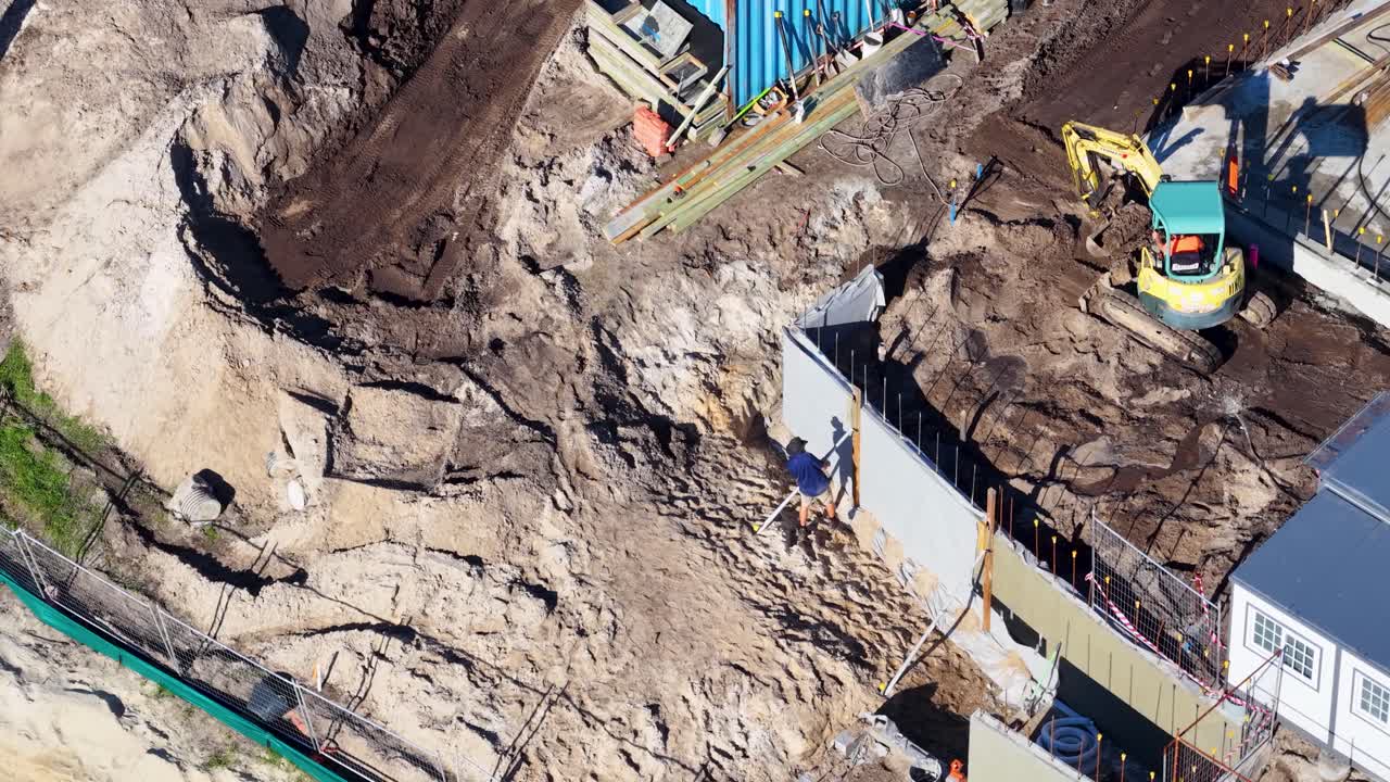 Drone footage captures workers and machinery at a construction site in Gold Coast, Australia, with clear skies and vibrant lighting