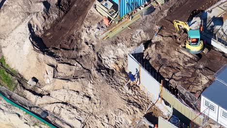 drone footage captures workers and machinery at a construction site in gold coast, australia, with clear skies and vibrant lighting