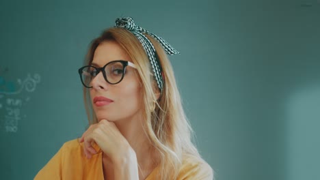 portrait of a blonde woman wearing glasses and a headscarf