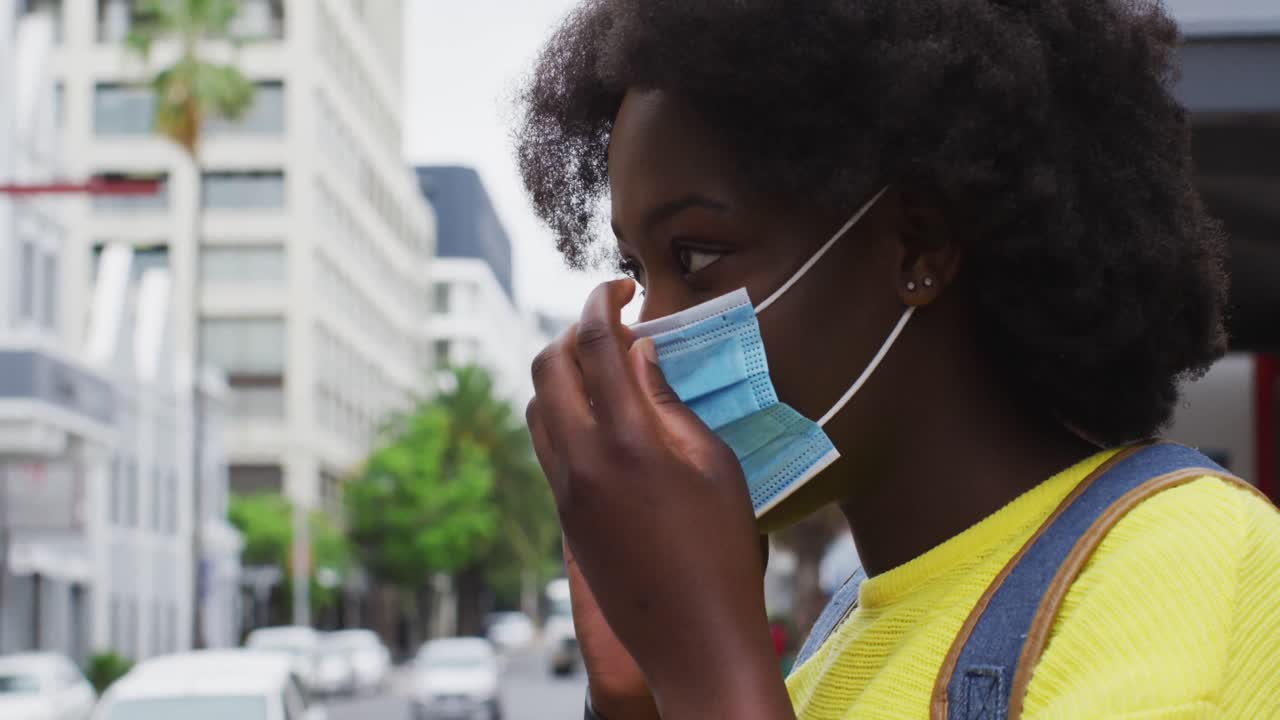 African american putting her mask on in street