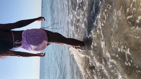 mujer negra irreconocible caminando por la playa