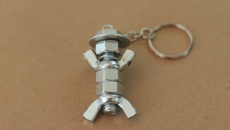 silver keychain crafted to resemble a figure with hat, made from nuts and bolts