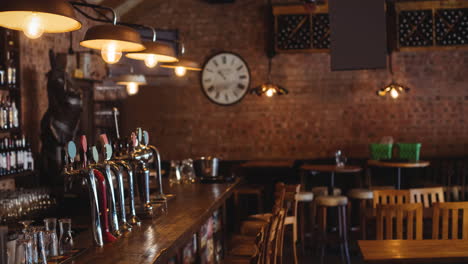 interior of empty bar or pub, with beer taps, wooden tables and chairs and exposed brick wall