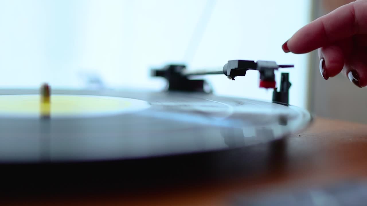 비닐 디스크로 오래된 레코드 플레이어를 시작하는 여성의 클로즈업