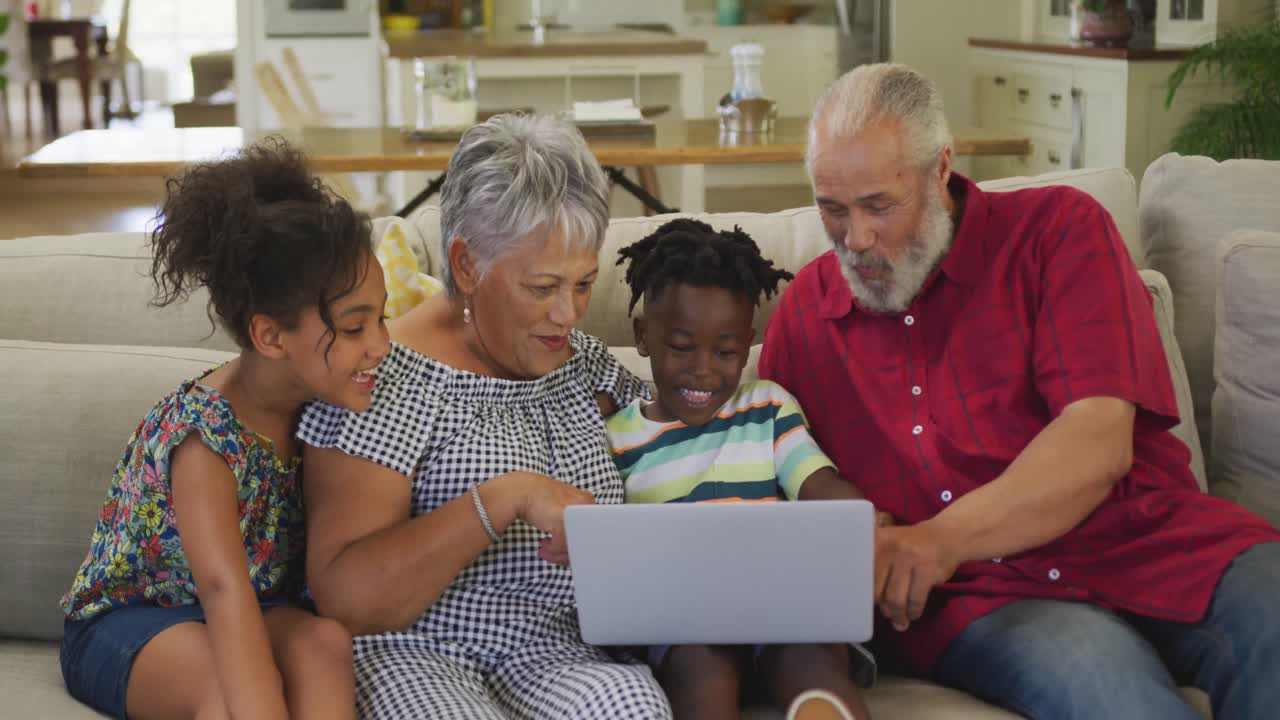 Grandparents and grandchildren using laptop at home