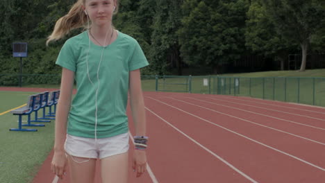 teen girl walks on a high school track smiling to herself in slow motion