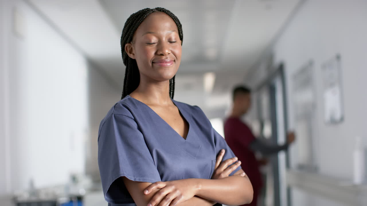 Portrait of happy african american female doctor wearing scrubs in hospital, slow motion