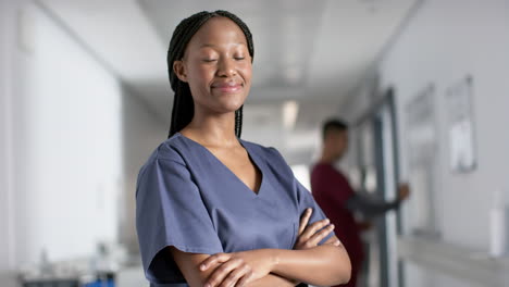 Portrait-of-happy-african-american-female-doctor-wearing-scrubs-in-hospital,-slow-motion