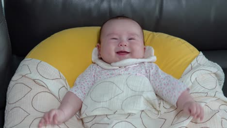 angry disturbed baby lying on the soft rototo cushion inside the house a close-up shot