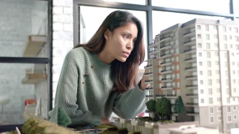 mujer de negocios casual enfocada en inspeccionar el modelo de la ciudad en la oficina en cámara lenta
