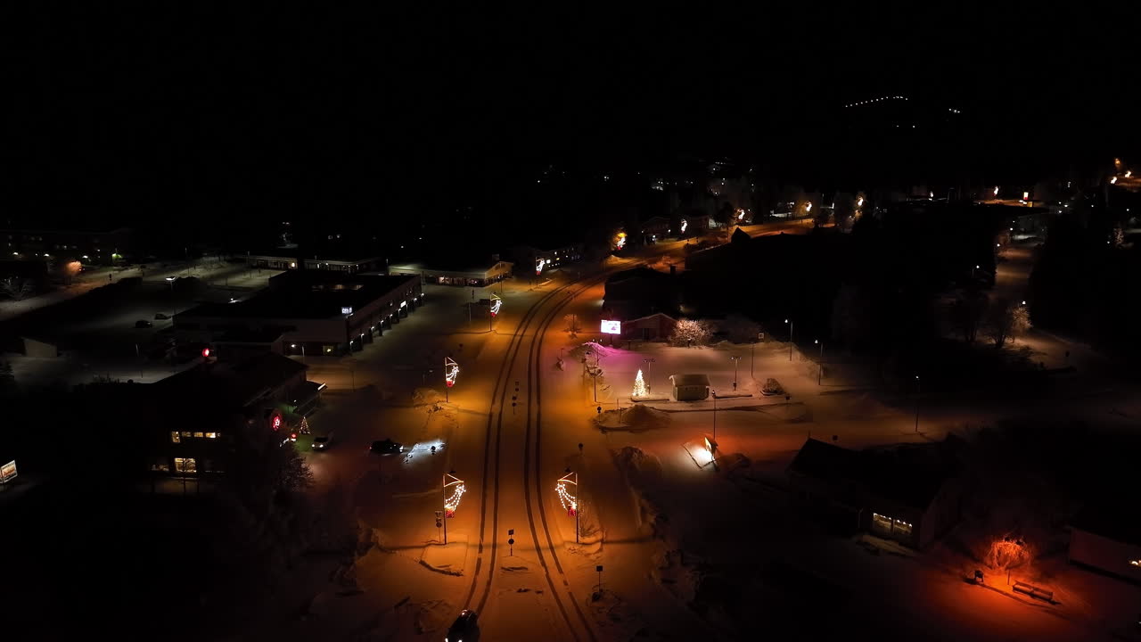 Aerial View of a Snow-Covered Town at Night with Christmas Lights