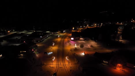 aerial view of a snow-covered town at night with christmas lights