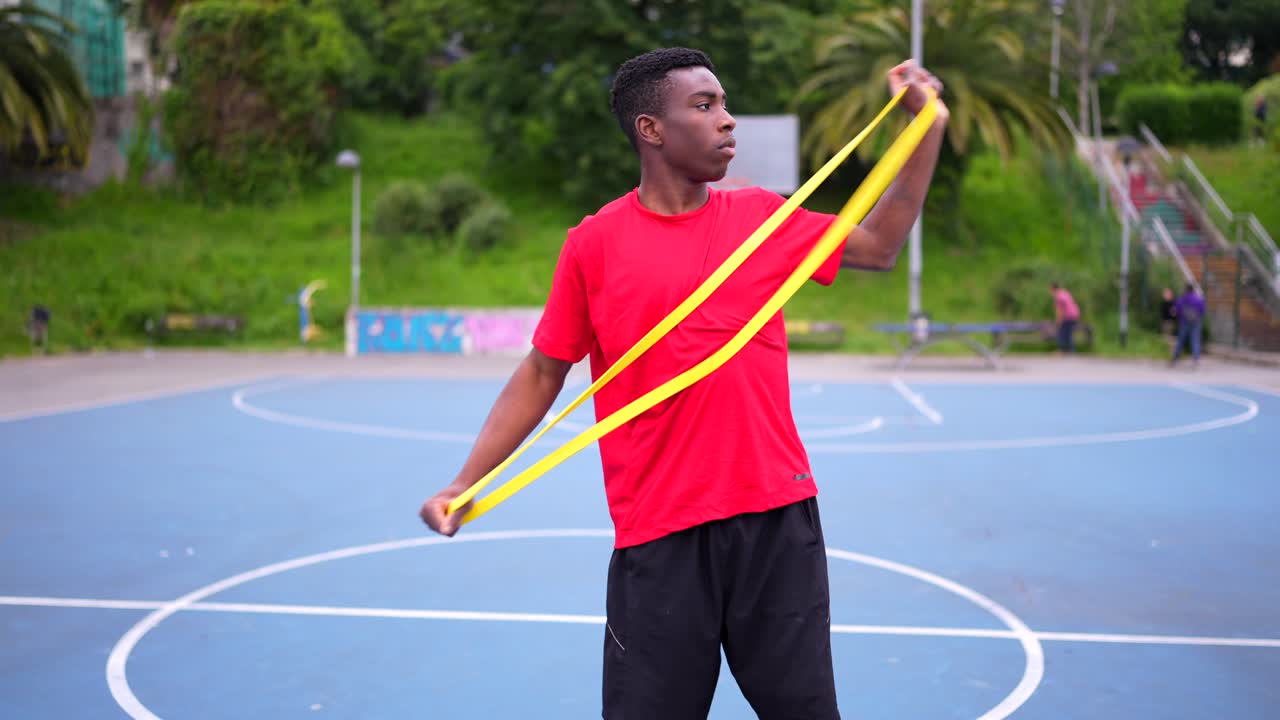 Man exercising with resistance band on basketball court