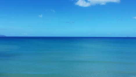 aerial drone shot of a surfer riding the waves with a perfect blue horizon in the background.