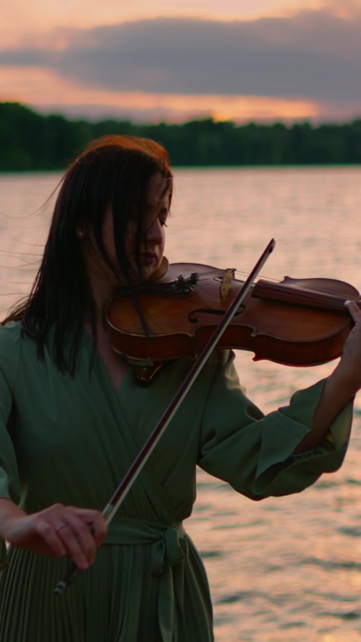 Woman Playing Violin by the Lake at Sunset
