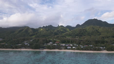 Gradual aerial approach to coastline with towering tropical mountains above beaches, Rarotonga Cook Islands