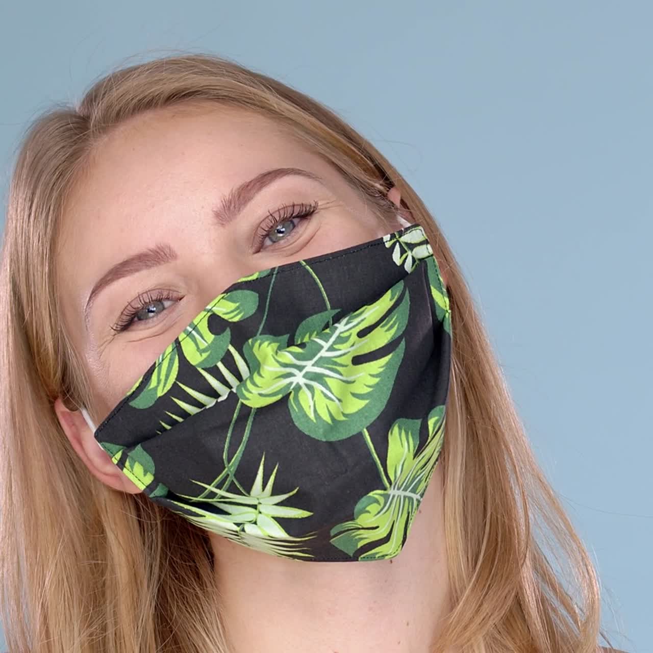 Retrato de estudio de mujer joven con mascarilla facial estampada con flores, mirando a cámara en primer plano