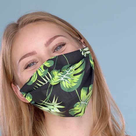 Studio-portrait-of-young-woman-wearing-a-face-flower-patterned-mask--looking-at-camera--close-up