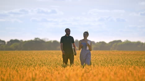 Agriculture-engineer-walking-with-female-student-in-wheat-field-at-summer