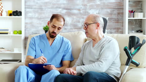 pensioner talking about his health problem with a male nurse in bright nursing home