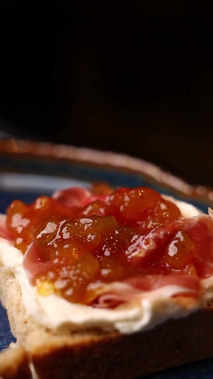 Cucchiaio che Spalma Marmellata di Fichi su Toast con Prosciutto e Formaggio Spalmabile