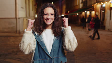 happy girl showing thumbs up like sign celebrate win victory good positive feedback in city street