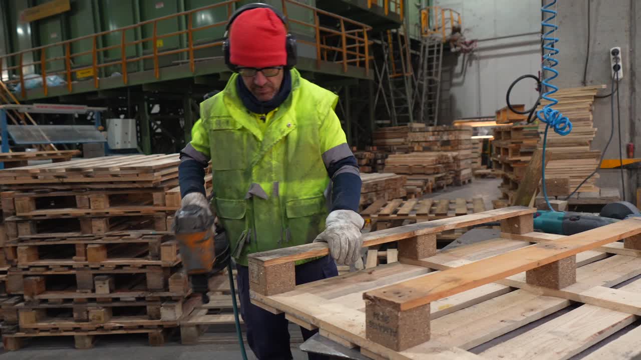 Worker assembling pallets in a factory