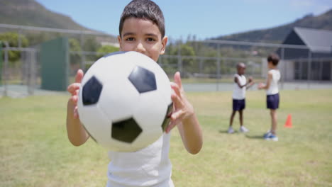 holding soccer ball, child playing outdoors with friends at school field