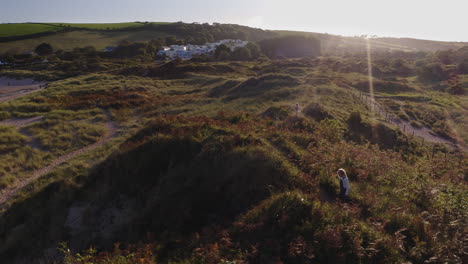 Drone-Shot-Of-Young-Girls-On-Beach-Vacation-Playing-In-Sand-Dunes-Against-Flaring-Sun