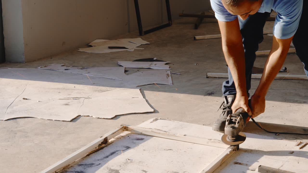 Trabalhador esmerilhando estrutura de metal para reparo na oficina. Plano médio.