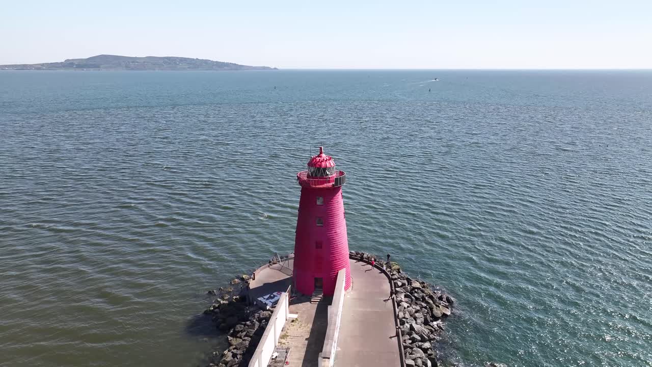 Poolbeg Lighthouse aerial pull back from iconic building in Dublin, Ireland with long walkaway