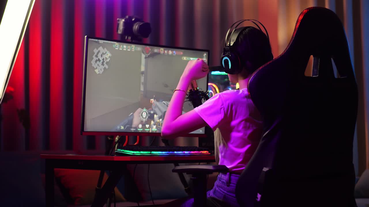Back View Of Asian Girl Streamer Screaming Goal And Dancing Celebrating Winning Game Over Network On Personal Computer.  Live Stream Video Game, Desk Illuminated By Rgb Led Strip Light