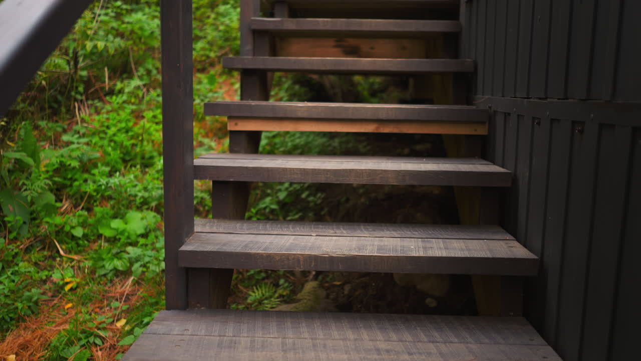 escalera de madera de la casa de campo. elemento para el ascenso y descenso en el edificio del complejo de glamping para turistas rodeado de denso bosque con plantas