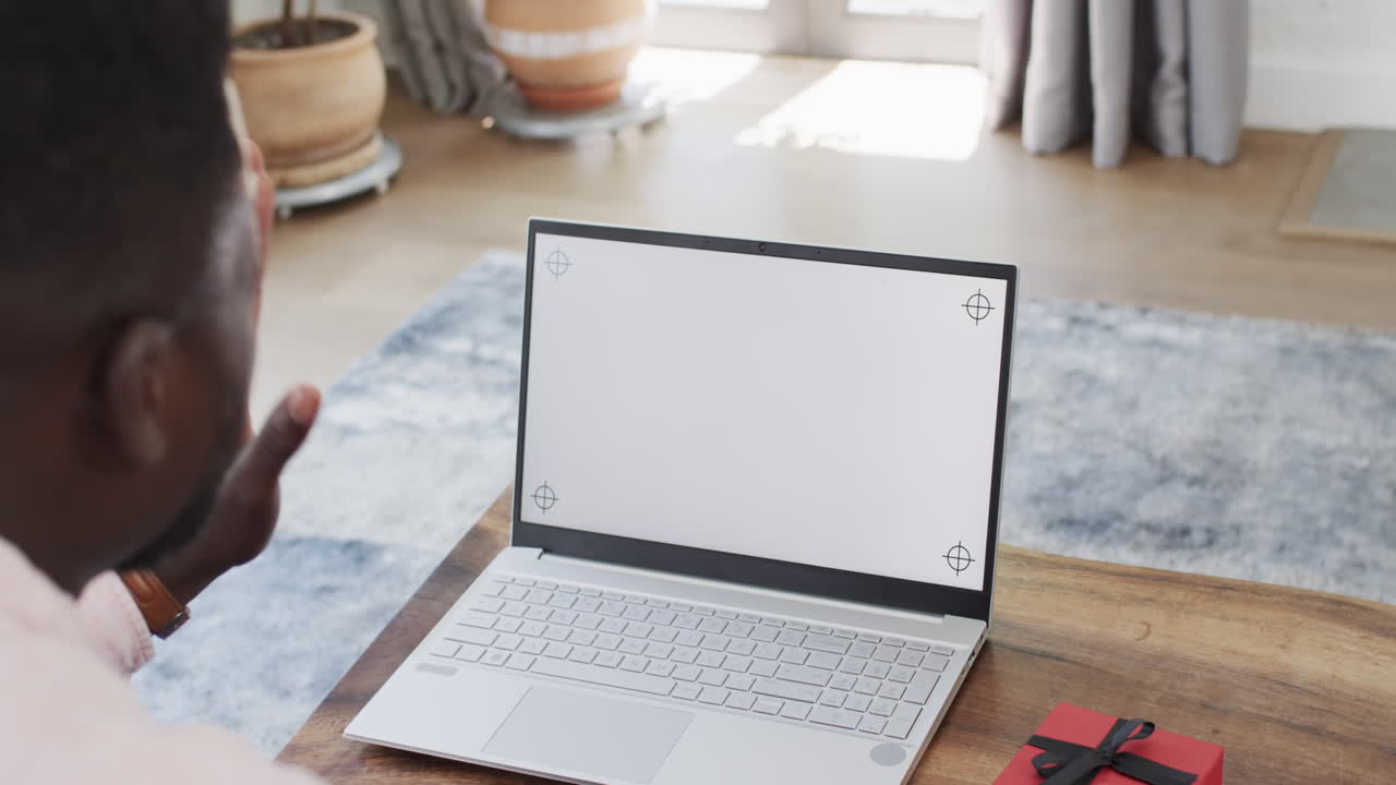 African American man using a laptop at home on a video call, with copy space
