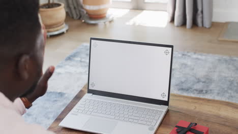 african american man using a laptop at home on a video call, with copy space