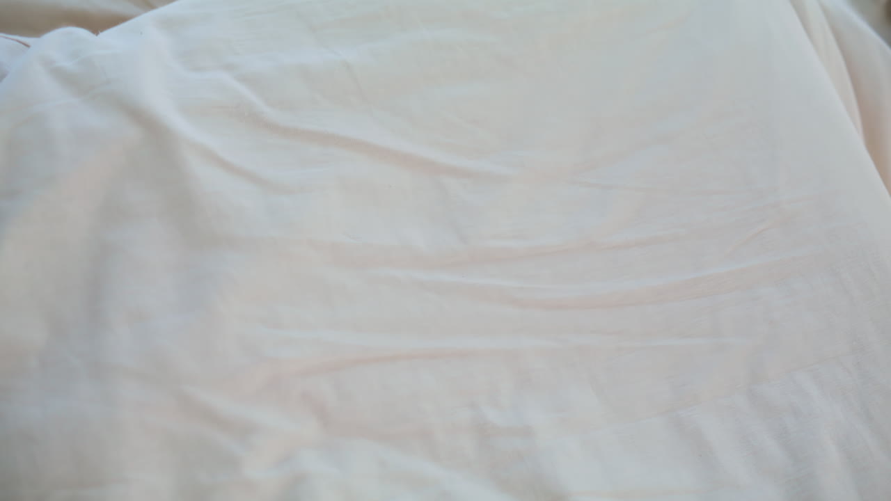 Primo piano di una donna allegra sdraiata sui cuscini che si gode il risveglio mattutino in un appartamento luminoso