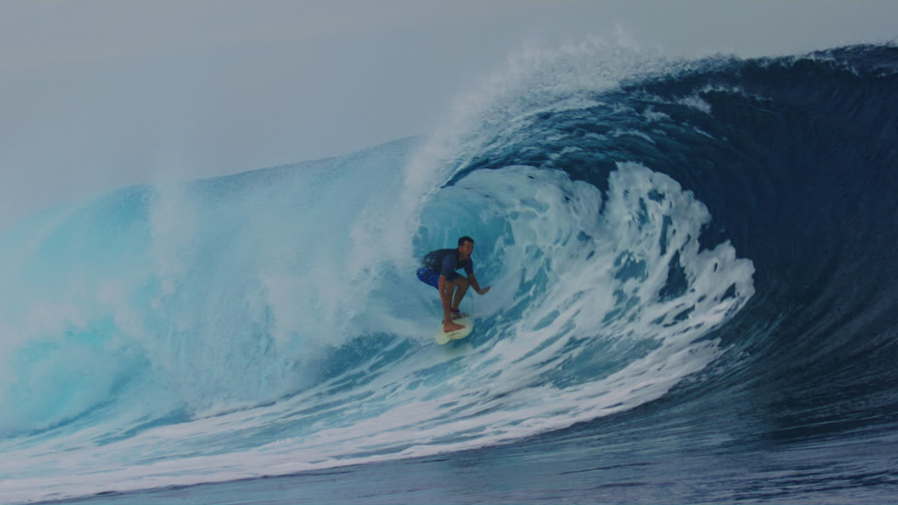 una ola espumosa rompiendo bajo cielos nublados, con un dramático paisaje costero en fiji, el surfista se desliza hacia abajo con la cara metida debajo del labio en el barril