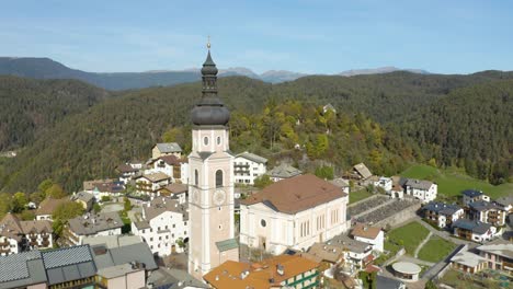 Drone-Flies-Past-Church-in-Small-Mountain-Village-in-Dolomites