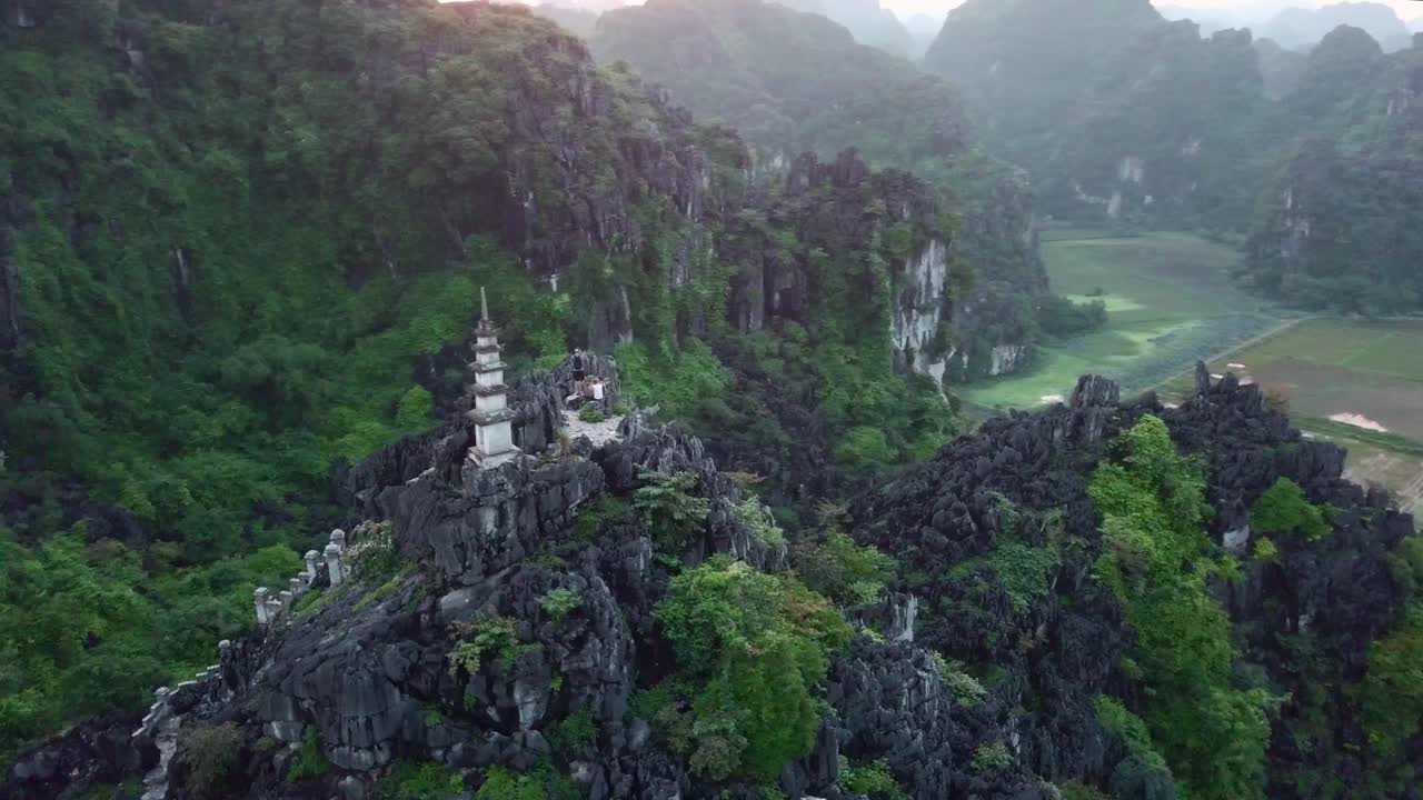 A temple on a top of an mountain in Vietnam surrounded by a drone