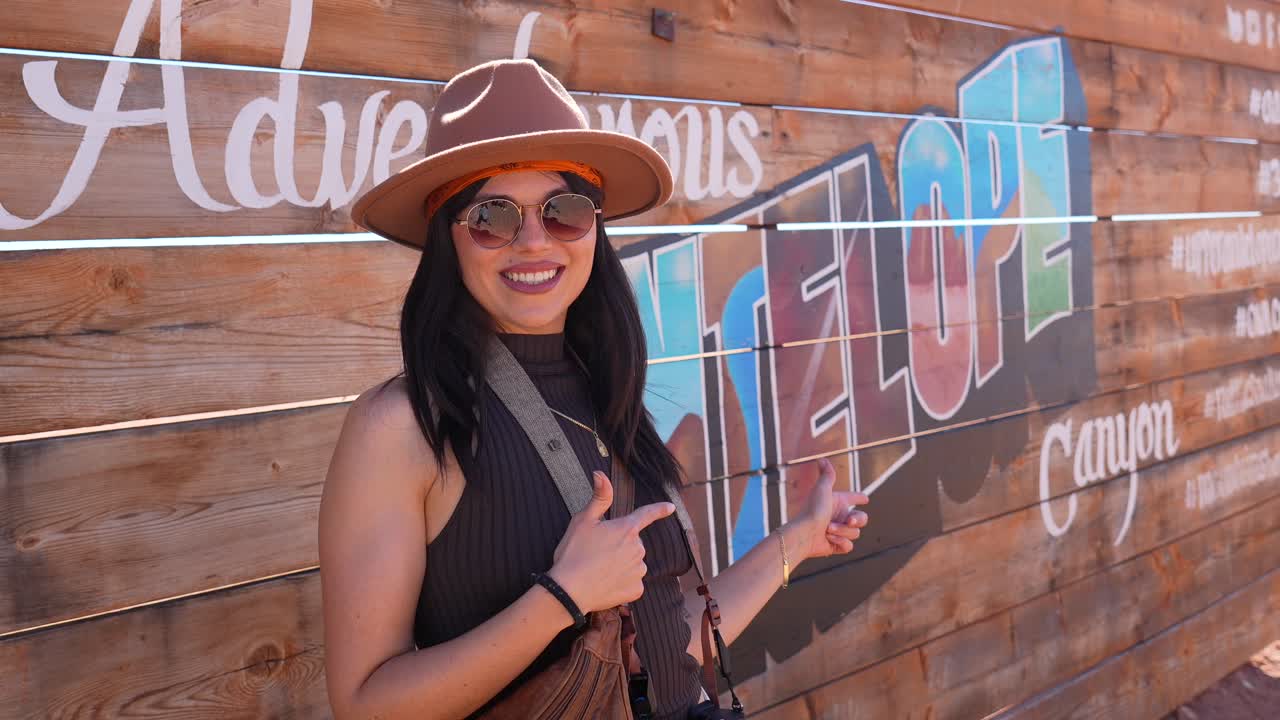 Giovane donna in posa e che indica il cartello dell'avventuroso Antelope Canyon