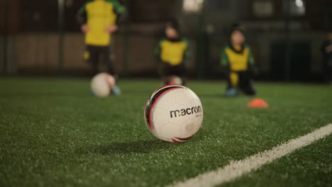 a children's football team trains at the stadium under the guidance of a coach. kids in sports uniforms practice ball exercises, improve technique, and develop teamwork on the green field