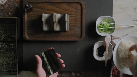 top down shot of a chef preparing sushi hand rolls