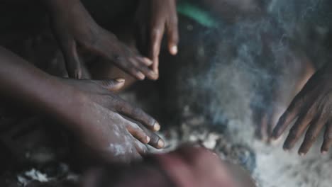 Group-Of-Dark-Skinned-hands-Warming-Themselves-Around-A-Fireplace-during-cold-day,close-up