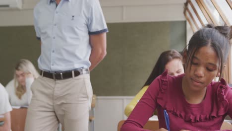 el maestro caminando mientras los estudiantes de secundaria están escribiendo