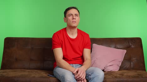 sad man sitting on sofa, waiting for message on green screen